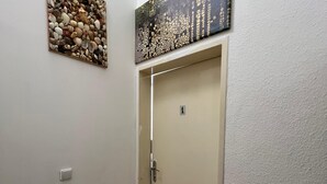 Un couloir avec une porte, un paillasson et deux œuvres d’art murales.