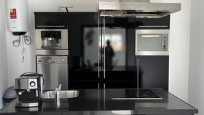 Una cocina moderna con una isla central, horno empotrado, microondas y cafetera.
