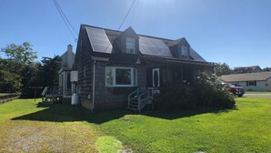 A two-story house with a front porch, a visible staircase, and a solar panel on the roof.