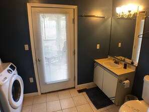 A bathroom with a washing machine, a sink, a toilet, and a mirror.