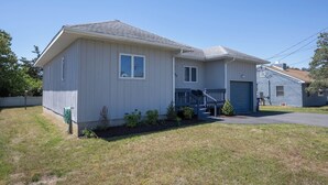 Ett enplanshus med en veranda på framsidan, ett garage och en liten trädgård framför huset.