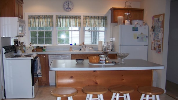 A kitchen with a central island, stools, a dishwasher, a refrigerator, and a clock on the wall. - Just a block to the beach!  701 Cedar (Lewes)