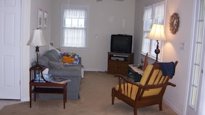 A living room with a sofa, armchair, television, and a ceiling fan. - Just a block to the beach!  701 Cedar (Lewes)