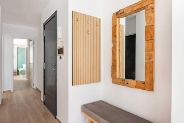 Un pasillo con un banco, una puerta y un espejo adosado a la pared.