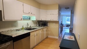 A kitchen with a granite countertop, stainless steel sink, and a dishwasher. There is a sign on the wall that says "BEACH". - 24 Dickinson Avenue, 8A Dewey Villas, Dewey Beach, Delaware (Dewey Beach)