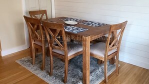 A dining table with six wooden chairs, a patterned tablecloth, and a grey rug on a wooden floor. - 24 Dickinson Avenue, 8A Dewey Villas, Dewey Beach, Delaware (Dewey Beach)