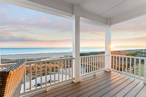A wooden deck with a white railing overlooking a beach at sunset. - Ocean Ridge - New Construction, 5 bedroom, 4.5 bath home, Ocean Front (Atlantic Beach)