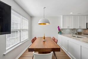 A modern kitchen with white cabinets, a wooden dining table, and a pendant light. - 1 Kendall Lane, Villas At Eagles Landing, Rehoboth Beach, Delaware (Rehoboth Beach)