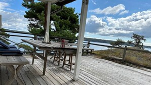 A wooden deck with a table and chairs, overlooking a body of water. - Seaside Bliss for Families: Home Away from Home (Stockholms län)