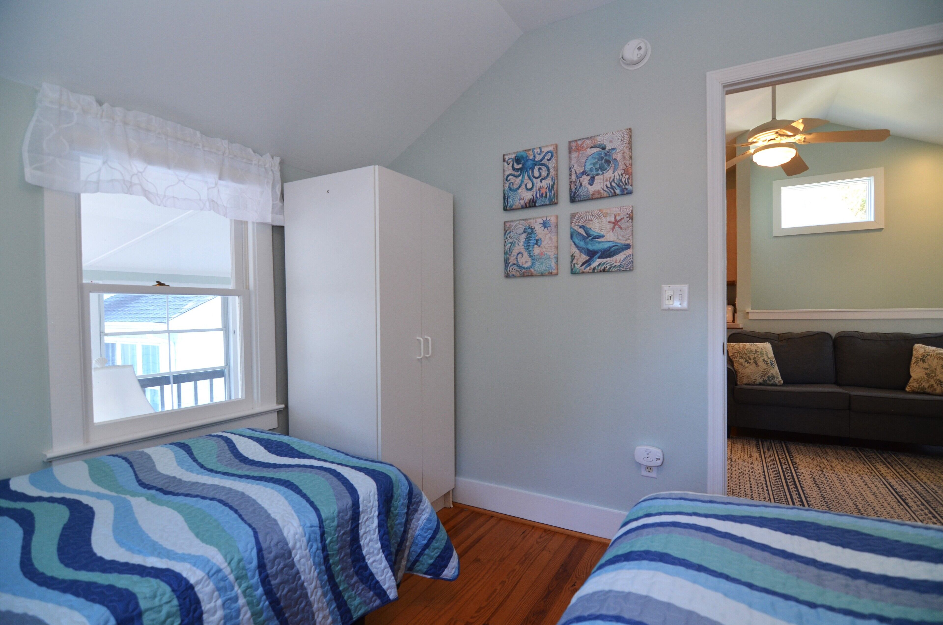 A bedroom with two beds, a wardrobe, and a window with a view.