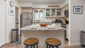 A kitchen with a central island, stainless steel appliances, and a 'Welcome to the Beach' sign.