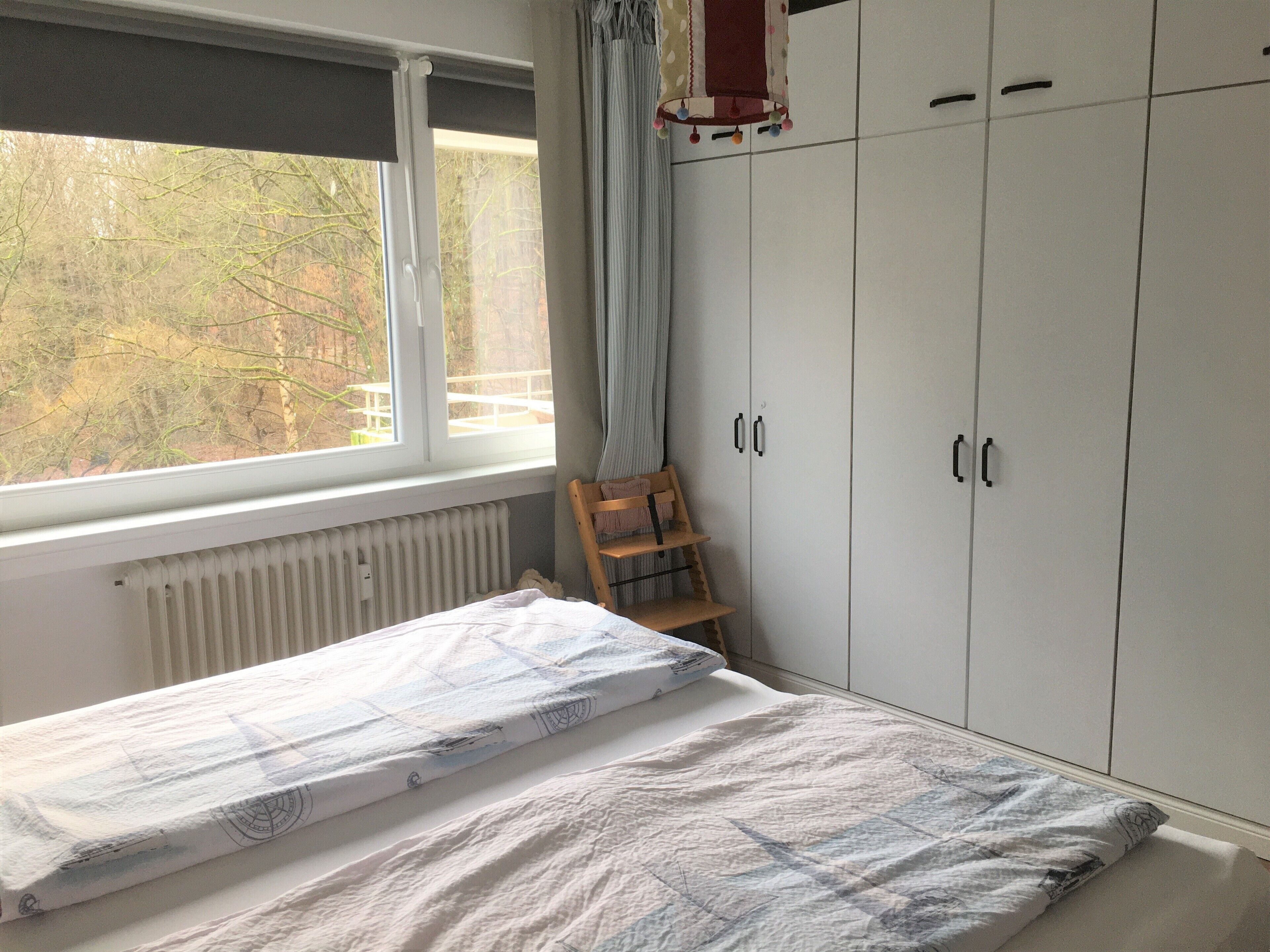 Une chambre à coucher avec un lit, une fenêtre, un radiateur et une armoire.