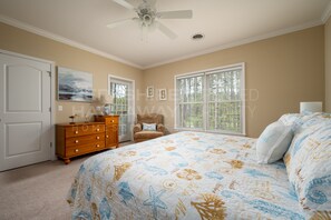 Une chambre à coucher comprenant un lit, une commode, une chaise et un ventilateur de plafond.