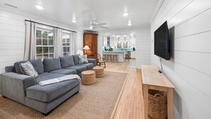 Ein modernes Wohnzimmer mit einem grauen Ecksofa, einem Holztisch und einem an der Wand befestigten Fernseher.