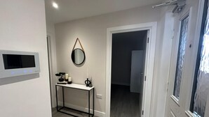 Un couloir avec une console, un miroir et une porte donnant sur une autre pièce.