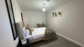 Une chambre moderne avec un lit, une table de chevet et un petit bureau avec une lampe.