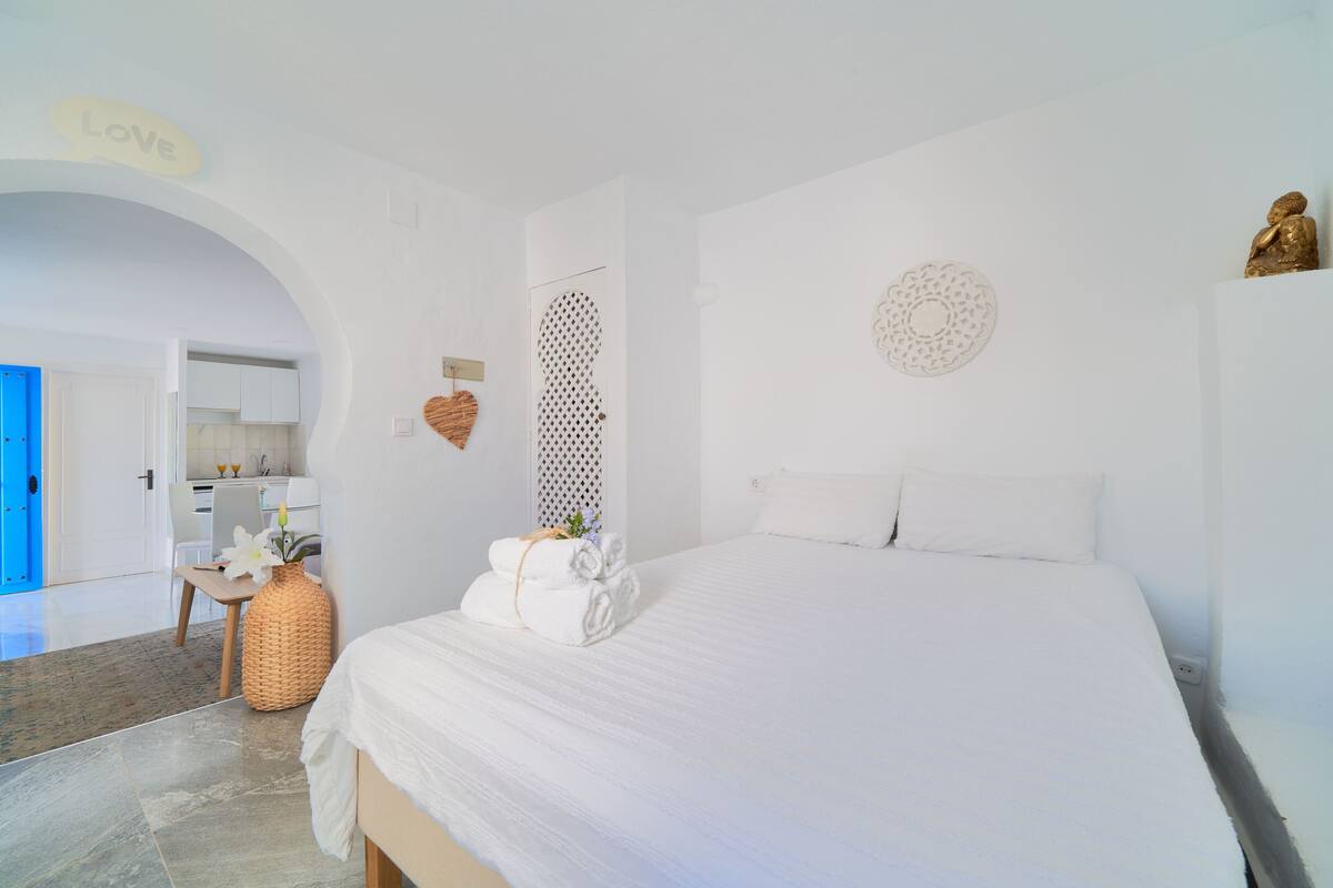 A bedroom with a bed, a bathroom, and a kitchen area.