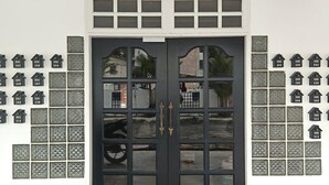 A dark-colored double door with multiple glass panels, flanked by decorative house-shaped tiles numbered 101 to 213. - Luna Hotel by Moonknight (George Town)