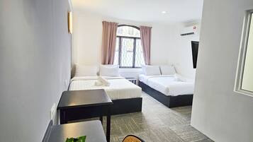 Habitación de hotel con dos camas, una mesa de comedor con una planta, una silla y una lámpara de techo.