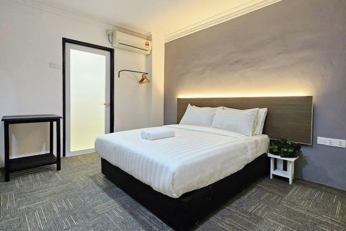 A neatly arranged hotel room with a bed, bedside table, and a small plant.