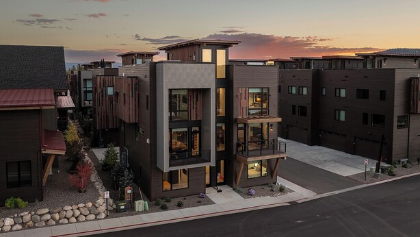 A modern multi-story residential building with a mix of balconies and large windows, set against a sunset sky. - US1211 | Modern Interiors | A/C | Roof Top Hot Tub (Steamboat Springs)