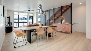 A modern dining area with a large table, chairs, and a view of a snowy landscape through large windows. - US1211 | Modern Interiors | A/C | Roof Top Hot Tub (Steamboat Springs)