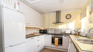 A compact kitchen with white cabinets, a Bosch refrigerator, a microwave, a toaster, and a sink.