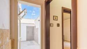 An open door leading to a tiled bathroom with a shower and a small window. - Casa Lory 1 near the sea (Nardò)
