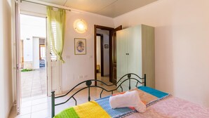 A bedroom with a bed, a door leading to a balcony, a wall-mounted light fixture, and a framed picture. - Casa Lory 1 near the sea (Nardò)