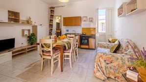 A compact living space with a dining area, kitchen, and a sofa. - Casa Lory 1 near the sea (Nardò)