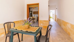 A dining area with a table set for two, a potted plant, and a view into the kitchen. - Casa Lory 1 near the sea (Nardò)