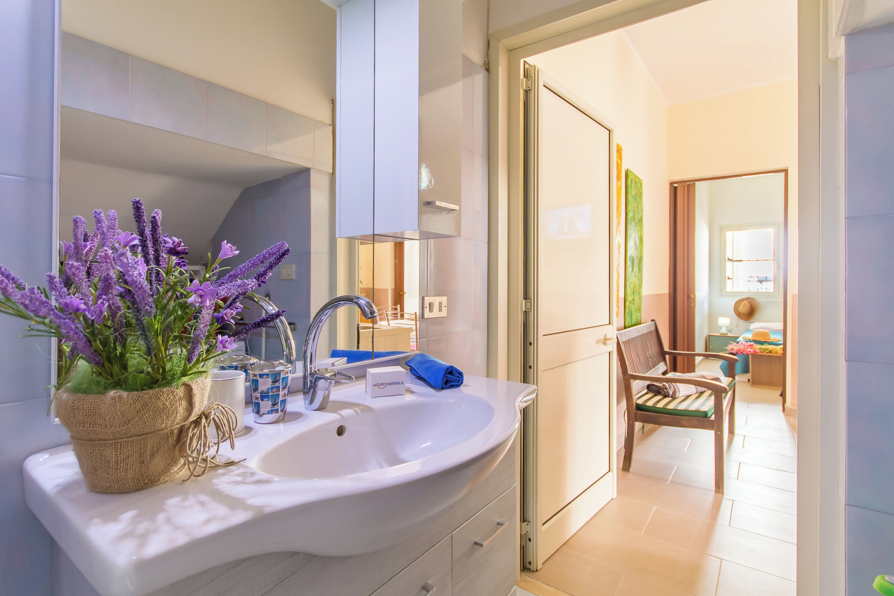 A bathroom with a sink, mirror, and a potted lavender plant.