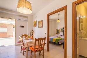 A dining area with a table set for two, a wooden chair, and a hanging lamp.