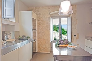 Una cocina con pared de piedra, ventana con vistas y una lámpara moderna.