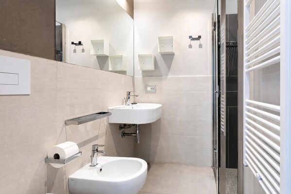 A modern bathroom with a sink, mirror, and toilet paper holder. - Villa Ficus (Scicli)