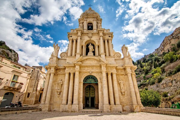 A historic church with a bell tower, arched entrance, and statues. - Villa Ficus (Scicli)