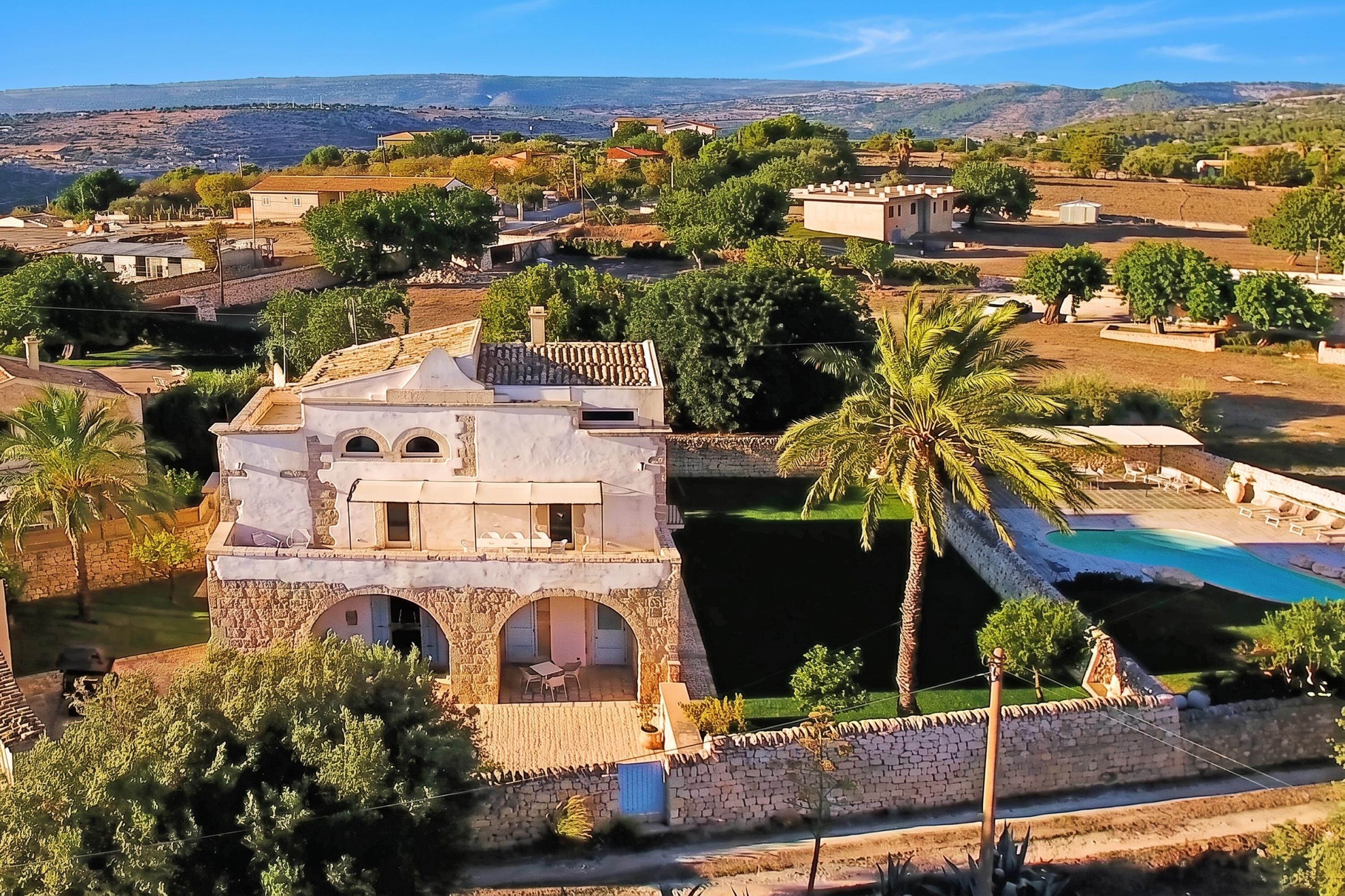 A villa with a stone tower, a swimming pool, and a view of the surrounding landscape.