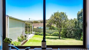 A view through a window of a backyard with a lawn, a tree, and a building. - Albatross-96 Albatross Ave Hayborough (Hayborough)