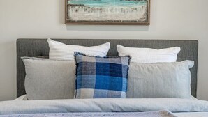 A bed with a grey headboard, two white pillows, and a blue and grey checkered pillow. - Albatross-96 Albatross Ave Hayborough (Hayborough)