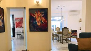 A spacious living area with a wooden floor, a green sofa, and a dining area with wooden chairs and a table. - Golden pearl - top center, luxurious, jacuzzi loft (Sofia)