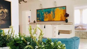 A living room with a blue sofa, a large abstract painting, and a white cabinet. - Golden pearl - top center, luxurious, jacuzzi loft (Sofia)