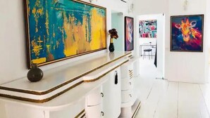 A hallway with a white reception desk, a large abstract painting, and a colorful giraffe painting on the wall. - Golden pearl - top center, luxurious, jacuzzi loft (Sofia)