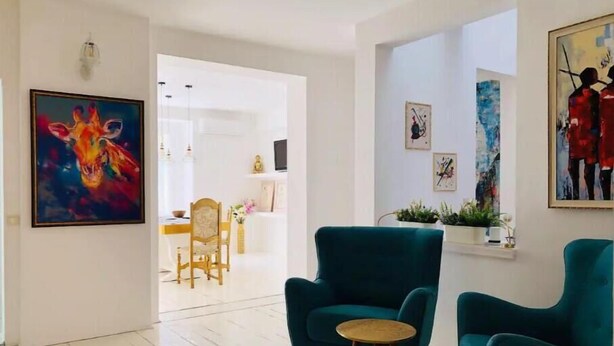 A spacious living room with teal armchairs, a wooden coffee table, and a dining area in the background. - Golden pearl - top center, luxurious, jacuzzi loft (Sofia)