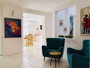 Un salón amplio con sillones color turquesa, una mesa de centro de madera y un comedor al fondo.