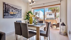 A dining area with a table set for four, a pineapple vase with flowers, and a cityscape painting on the wall.