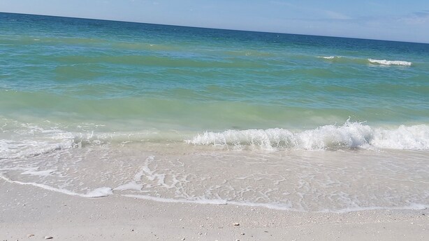 Une plage à l’eau turquoise et limpide, où les vagues sont douces.