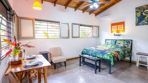 A bedroom with a bed, a desk, a chair, and a window with blinds. - Toucan Riverfront Villa with Pool Near A Beach (Uvita)