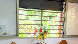 A wooden dining table with two chairs, a vase with flowers, and a bottle of liquor. - Toucan Riverfront Villa with Pool Near A Beach (Uvita)