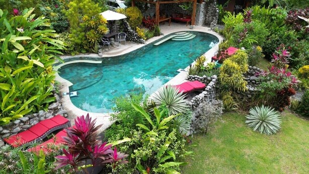 A swimming pool surrounded by lush greenery and a gazebo. - Toucan Riverfront Villa with Pool Near A Beach (Uvita)