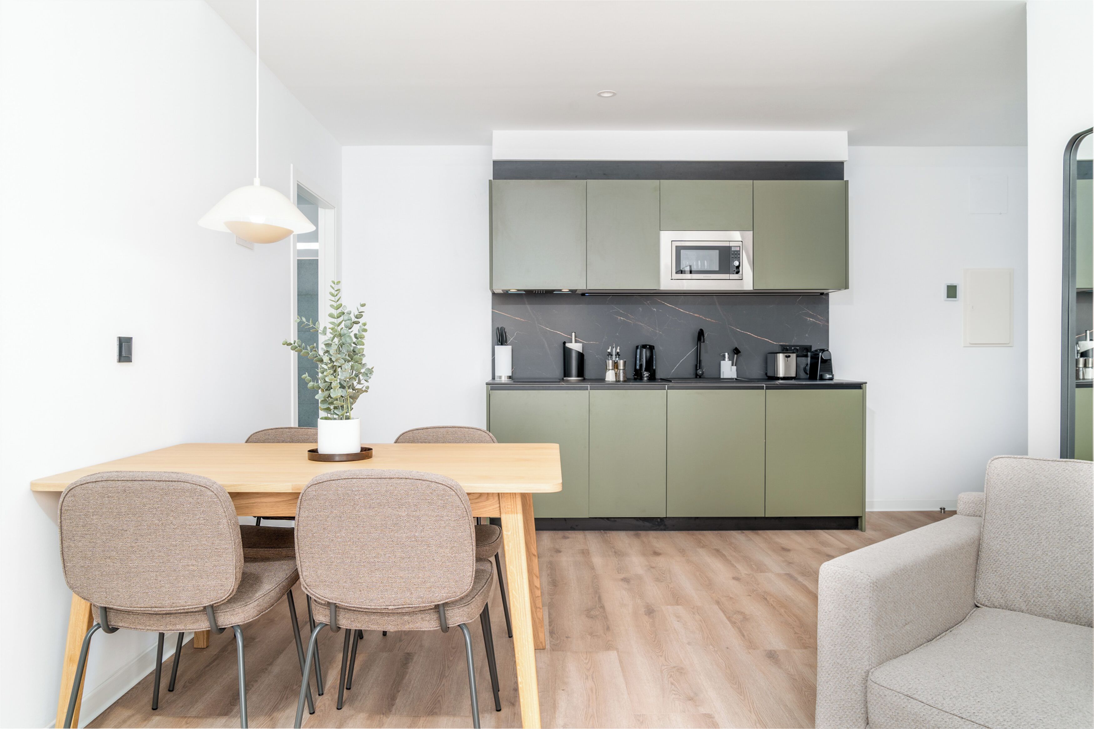 Una cocina moderna con armarios verdes, una mesa de comedor de madera y cuatro sillas.
